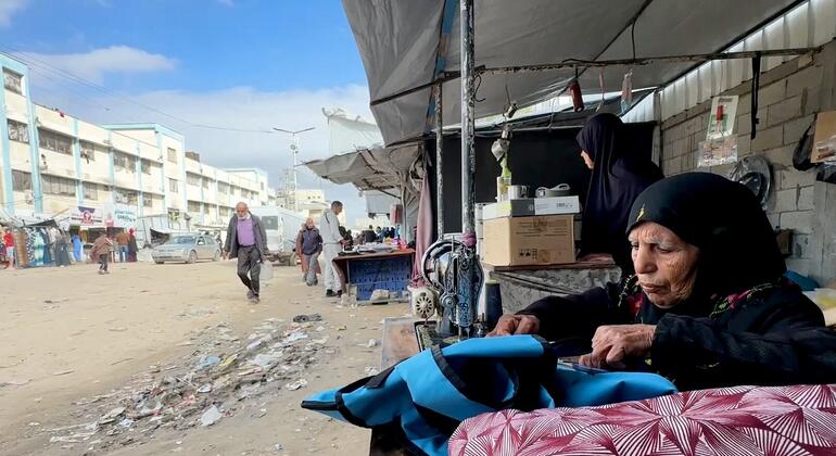 تجلس السيدة الفلسطينية المسنة، نغين بن عيسى، أمام ماكينة خياطة في شارع جلال في خان يونس، غزة، لإصلاح الملابس ودعم أسرتها بعد انقطاع المساعدات الاجتماعية بسبب الاضطرابات الناجمة عن الحرب.