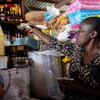 Dina, de 51 anos, beneficiária da assistência financeira do PMA em Canapé Vert, no Haiti, segurando dinheiro e um recibo enquanto comprava mercadorias para expandir seu pequeno negócio.