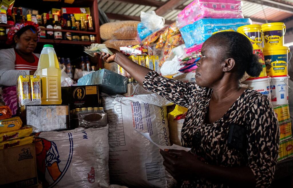 Dina, de 51 años, beneficiaria de la asistencia financiera del PMA en Canapé Vert, Haití, sosteniendo efectivo y un recibo mientras realiza compras para expandir su pequeño negocio.