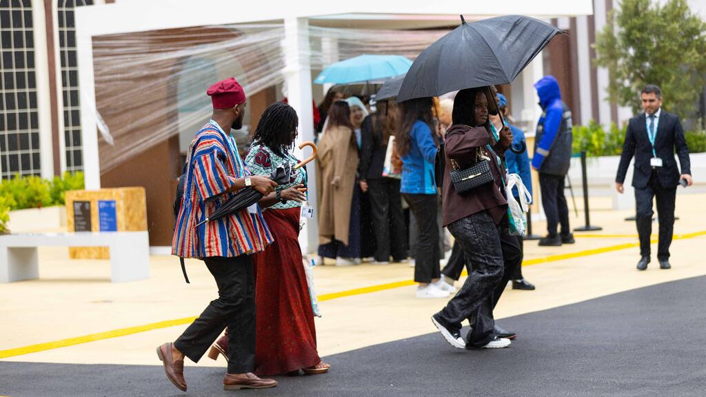 Attendees with umbrellas walk outside the venue at the World Urban Forum 13 (WUF13) in Baku, Azerbaijan.