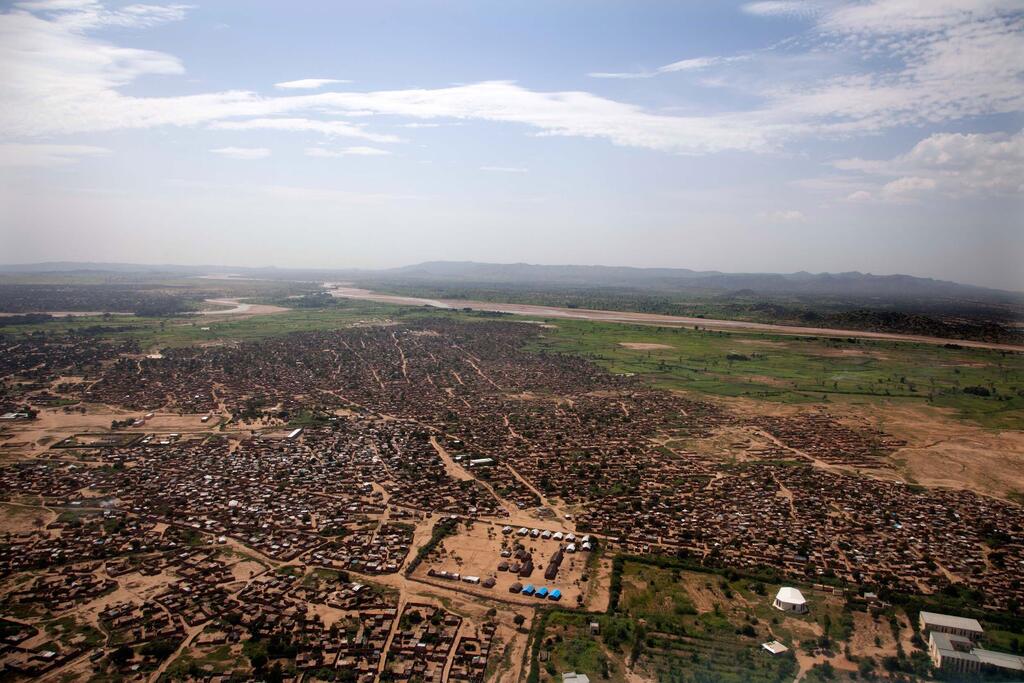 Vista aérea de la ciudad de Zalingei en Darfur Central, Sudán, que muestra un asentamiento extenso con edificios de ladrillo de barro, rodeado de tierras áridas y un río en la distancia, capturado el 18 de septiembre de 2013.