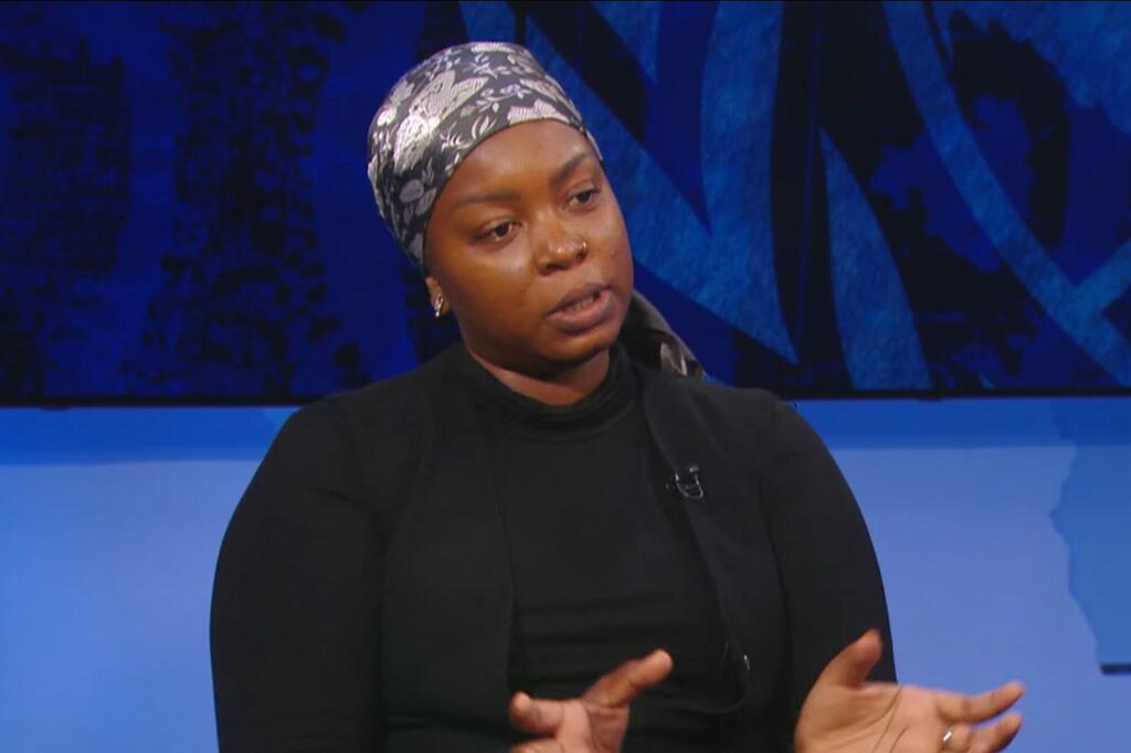Zahra Salehe, amevaa kofia ya kichwa na koti nyeusi, akizungumza na kufanya ishara wakati wa tukio.