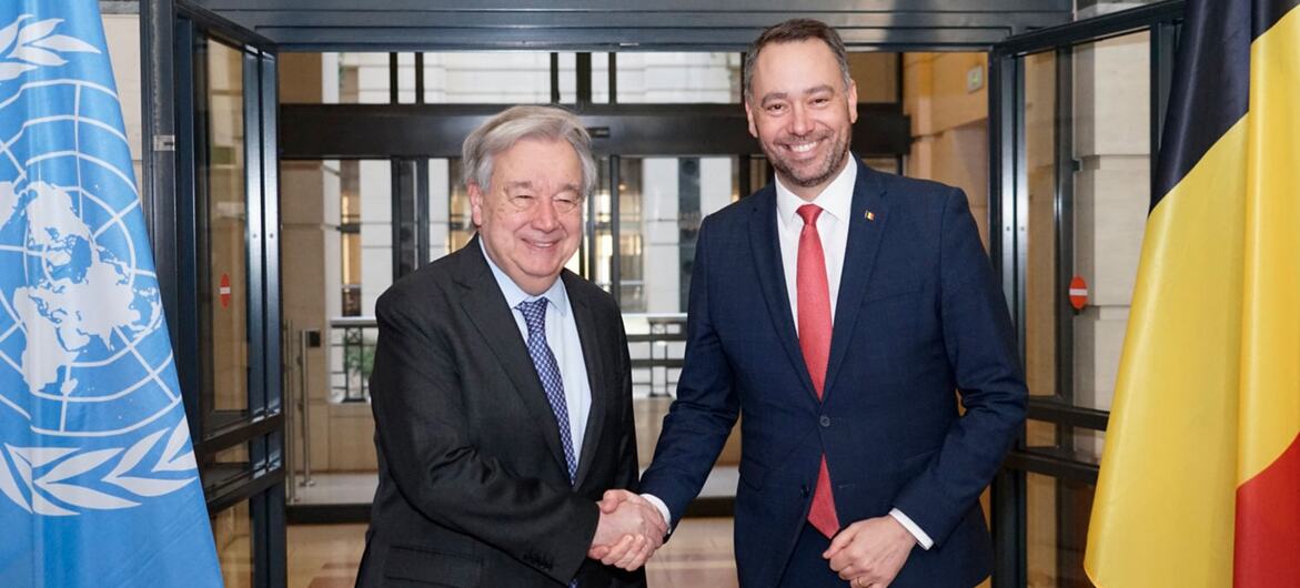 Le Secrétaire général António Guterres serre la main du ministre belge des Affaires étrangères, Emmanuel Hache, lors d'une réunion bilatérale à Bruxelles, le 18 mars 2026, avec les drapeaux de l'ONU et de la Belgique en arrière-plan.
