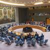صورة واسعة من غرفة مجلس الأمن التابع للأمم المتحدة تظهر المندوبين جالسين حول طاولة خشبية دائرية كبيرة مع لوحة جدارية كبيرة على الحائط خلفهم.