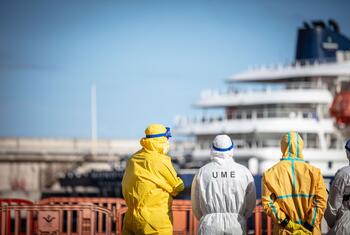 Des travailleurs de la santé en combinaisons de protection se tiennent sur un quai face à un navire de croisière lors de la réponse à une épidémie de hantavirus dans le port de Granadilla, à Ténérife, en Espagne.