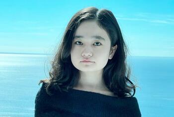 Portrait of Nila Ibrahimi standing outdoors with a snowy landscape and blue sky in the background.