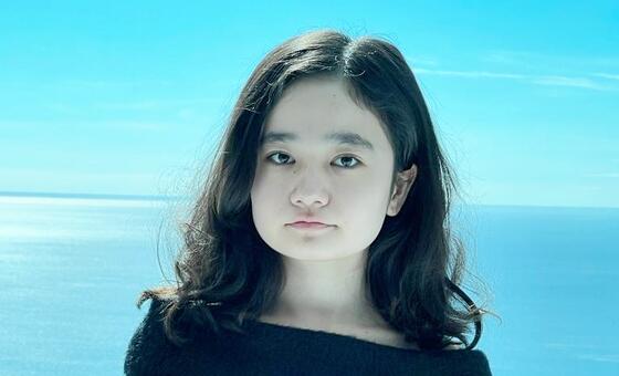 Portrait of Nila Ibrahimi standing outdoors with a snowy landscape and blue sky in the background.