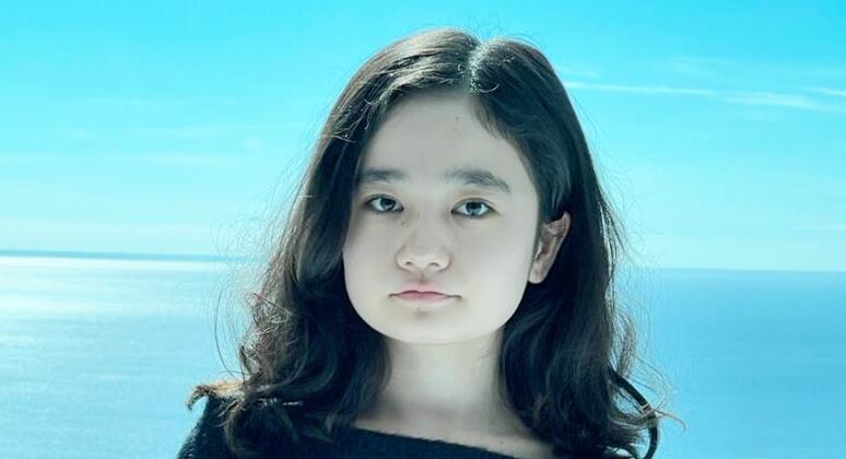 Portrait of Nila Ibrahimi standing outdoors with a snowy landscape and blue sky in the background.