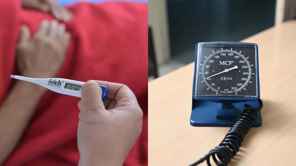 Una persona que sostiene un termómetro digital junto a un monitor de presión arterial de mercurio en una mesa.