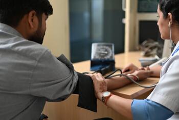 Un professionnel de la santé en Inde vérifie la pression artérielle d'un patient en utilisant un dispositif sans mercure, soulignant l'initiative de l'OMS pour un équipement médical sans mercure.