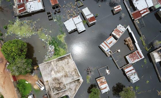 Imagem aérea de um drone do bairro de Magoanine, na cidade de Maputo, Moçambique, mostrando sérios danos causados por inundações com casas submergidas e detritos. Esta imagem captura o impacto das inundações catastróficas de janeiro de 2026, que afetaram centenas de milhares de pessoas e levaram a esforços nacionais de resposta de emergência pelo PMA e outras organizações humanitárias.