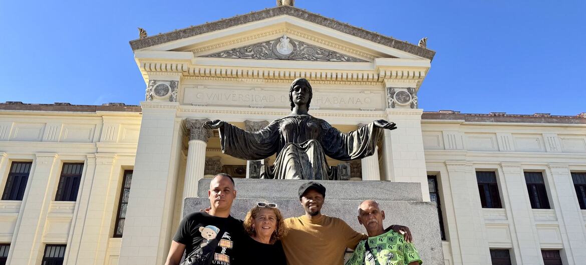 Quatre personnes posent pour une photo devant la statue de l'Université de La Havane à La Havane, à Cuba, mettant en évidence l'éducation swahili.