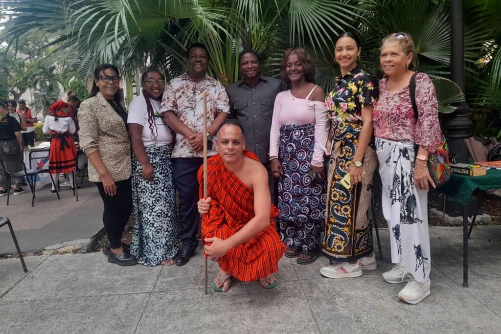 Kikundi cha watu, ikiwa ni pamoja na mwanamume aliyevaa mavazi ya Kiswahili ya jadi nyekundu akiwa ameshika fimbo, wakijipiga picha huko Havana, Cuba, wakati wa hafla ya elimu au utamaduni iliyozingatia lugha ya Kiswahili.