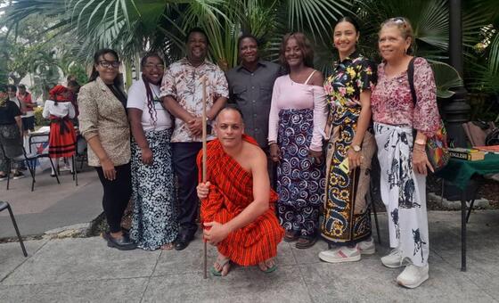 Kikundi cha watu, ikiwa ni pamoja na mwanamume aliyevaa mavazi ya Kiswahili ya jadi nyekundu akiwa ameshika fimbo, wakijipiga picha huko Havana, Cuba, wakati wa hafla ya elimu au utamaduni iliyozingatia lugha ya Kiswahili.