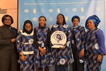 Wanawake sita, wakiwemo mahakimu wa Tanzania, wanapiga picha kwenye hafla ya CSW70. Mwanamke mmoja ana bamba la tuzo kwa Chama cha Mahakimu wa Wanawake wa Tanzania. Nyuma ina nembo za UN na kampeni 'Stop. Prevent. Protect.'
