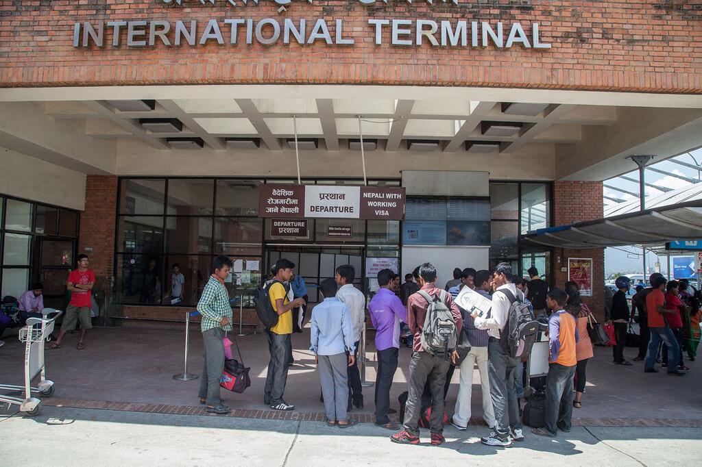 Un groupe de travailleurs migrants népalais attend devant le terminal international de l'aéroport de Katmandou, se préparant à partir pour travailler au Moyen-Orient.