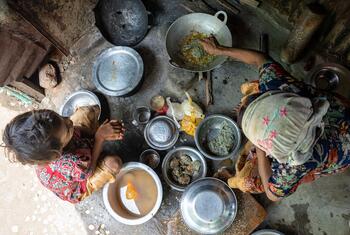 सिटवे, म्यांमार में एक शिविर में एक गर्भवती रोहिंग्या महिला अपने परिवार के लिए खाना बना रही है।
