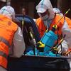 Des travailleurs équipés de tenues de protection et de gilets orange préparent le matériel de pulvérisation de pesticides à Gaza.