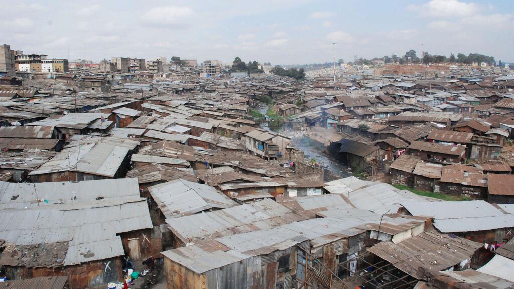 Vue aérienne d'un quartier pauvre densément peuplé de Nairobi, au Kenya, montrant des rangées de maisons précaires avec des toits en tôle ondulée.