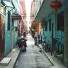 Um beco estreito com edifícios coloridos na China, com scooters e bicicletas estacionados.