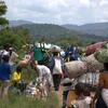 Un groupe de réfugiés et de demandeurs d'asile, dont des enfants, portent leurs affaires sur la tête et le dos alors qu'ils traversent un champ verdoyant au Burundi, fuyant la violence dans l'est de la RDC.