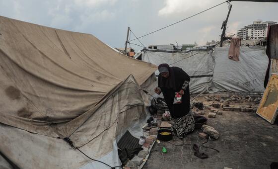 Hunger and malnutrition rates remain alarmingly high across Gaza Strip. Pictured here, a woman prepares food in Gaza City after a night of rain and wind.