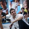 Un joven sonriente con una camisa blanca se sienta frente a un grupo de personas aplaudiendo, en un evento de diálogo juvenil celebrado en la oficina de UNICEF en Tailandia en febrero de 2024.