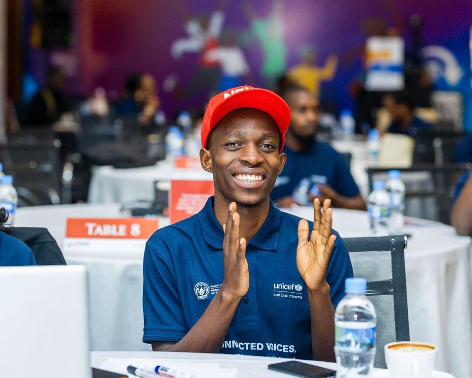 Jacques Kwibuka, mfanyakazi wa kujitolea wa UNICEF, anapiga makofi kwa shauku kwenye tukio la mtandao wa elimu.