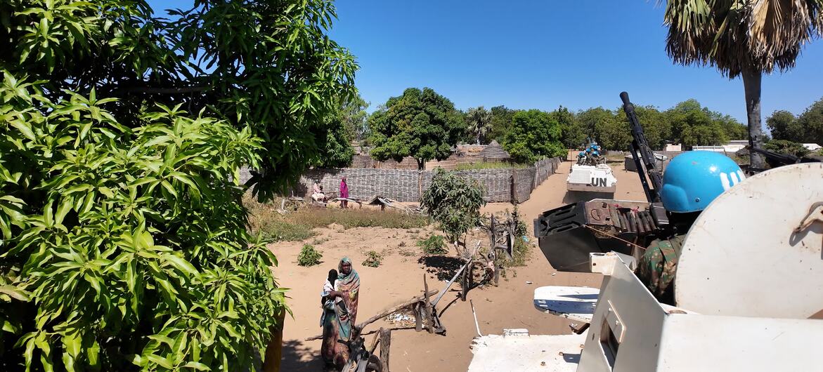 Um veículo de manutenção da paz da ONU patrulha uma área inundada na República Centro-Africana, com forças da MINUSCA navegando no terreno em meio a infraestrutura escassa e moradores locais nas proximidades.