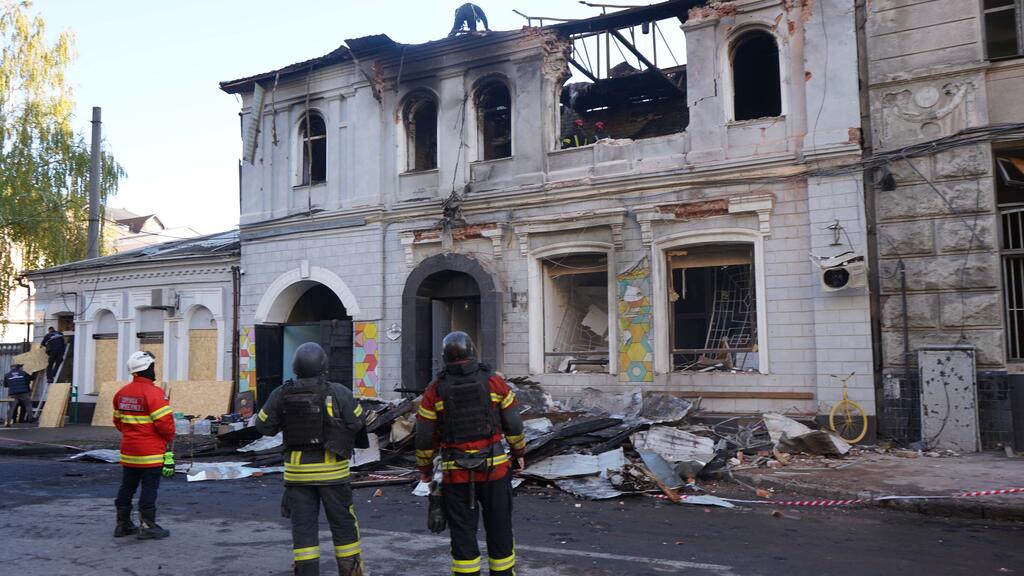 Firefighters in Ukraine inspect a heavily damaged building after a conflict incident, surrounded by debris and destruction.