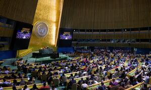 A wide view of the United Nations General Assembly hall during the opening of the Permanent Forum on Indigenous Issues (UNPFII). The room is filled with attendees seated at curved desks, facing a central podium under the large UN emblem.
