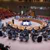 Uma ampla vista de alto ângulo da câmara do Conselho de Segurança das Nações Unidas durante uma reunião sobre a manutenção da paz e da segurança da Ucrânia. Os delegados estão sentados em torno da icônica mesa em formato de ferradura, com um feed de videoconferência visível em uma tela no centro.