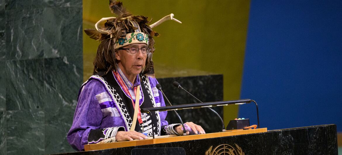 Tadodaho Sid Hill, chef de la nation Onondaga, portant des vêtements traditionnels, y compris un coiffe à bois de renne, s'exprimant à un tribune ornée de l'emblème des Nations Unies lors de l'ouverture de la 25e session du Forum permanent sur les questions autochtones.