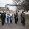 Группа людей, включая Ванессу Фрейзер, осматривает территорию сильно повреждённого здания в Украине и оценивает масштаб разрушений.
