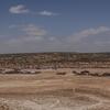 Wide view of the Karashal IDP camp in a desert landscape, showing rows of temporary shelters and tents under a clear sky.