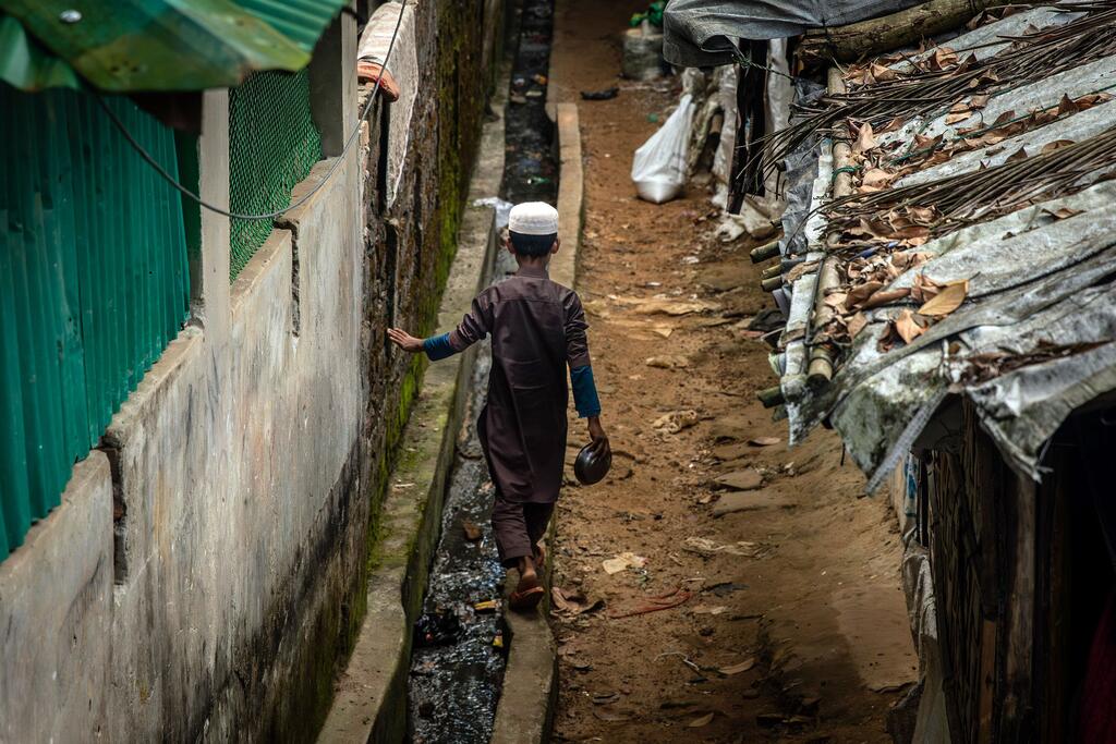 Un jeune enfant rohingya marche le long d'un sentier étroit entre des abris de fortune dans le camp de réfugiés de Cox's Bazar.
