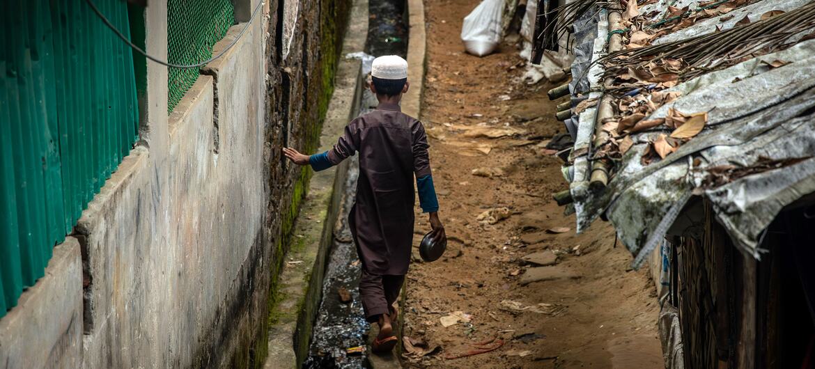 Un jeune enfant rohingya marche le long d'un sentier étroit entre des abris de fortune dans le camp de réfugiés de Cox's Bazar.