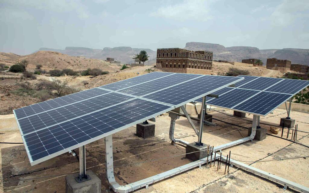 Photovoltaic solar panels installed on a rooftop in a desert landscape in Yemen, part of a UNOPS project to provide renewable energy.