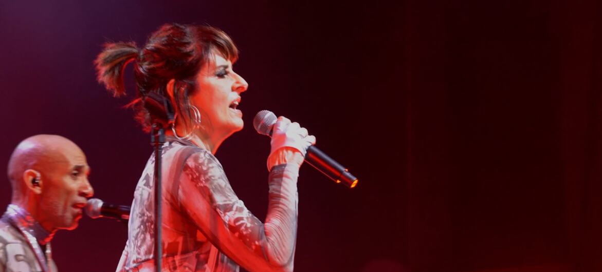 A cantora Fernanda Abreu se apresenta no palco com um microfone.  