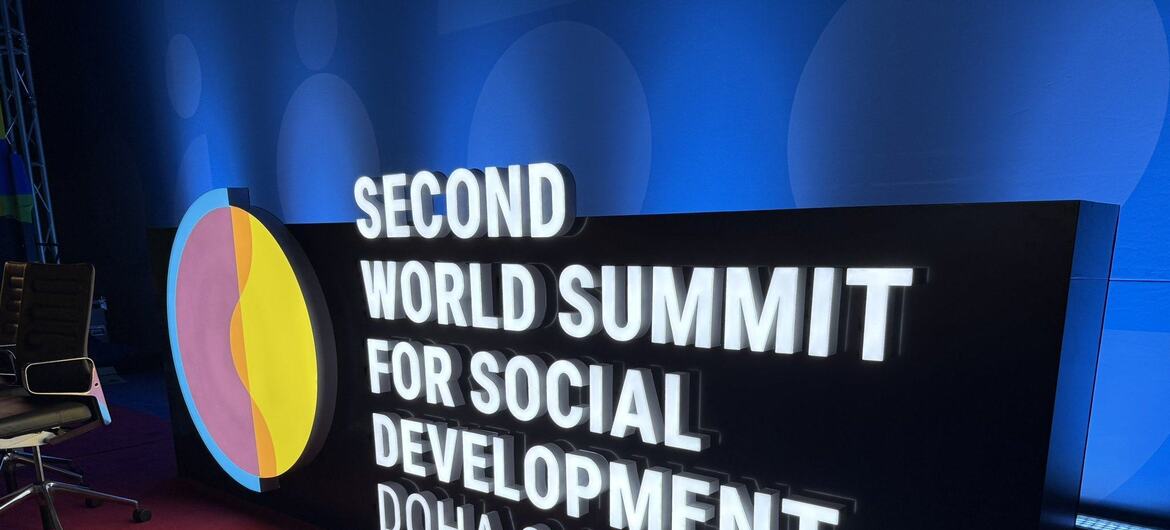A large, illuminated sign for the 'Second World Summit for Social Development, Doha 2025' is displayed on a red and blue carpeted floor.