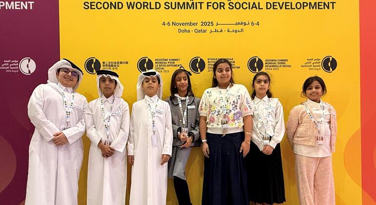 سبعة أطفال، بعضهم يرتدي الزي القطري التقليدي، يقفون أمام لافتة خاصة بالقمة العالمية الثانية للتنمية الاجتماعية في الدوحة.