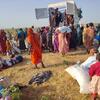 Displaced people in Sudan receive humanitarian aid from a UN truck in an open field.