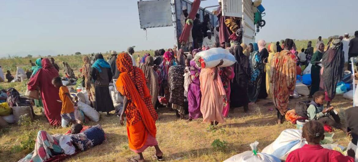 Personas desplazadas en Sudán reciben ayuda humanitaria de un camión de la ONU en un campo abierto.