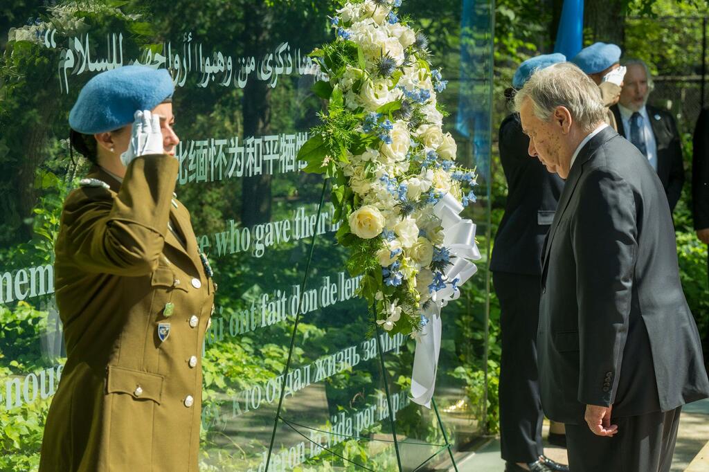 Le secrétaire général de ONU, António Guterres, et une soldate de la paix en uniforme lors d'une cérémonie de dépôt de gerbes en hommage aux soldats de la paix tombés au combat au siège de ONU .