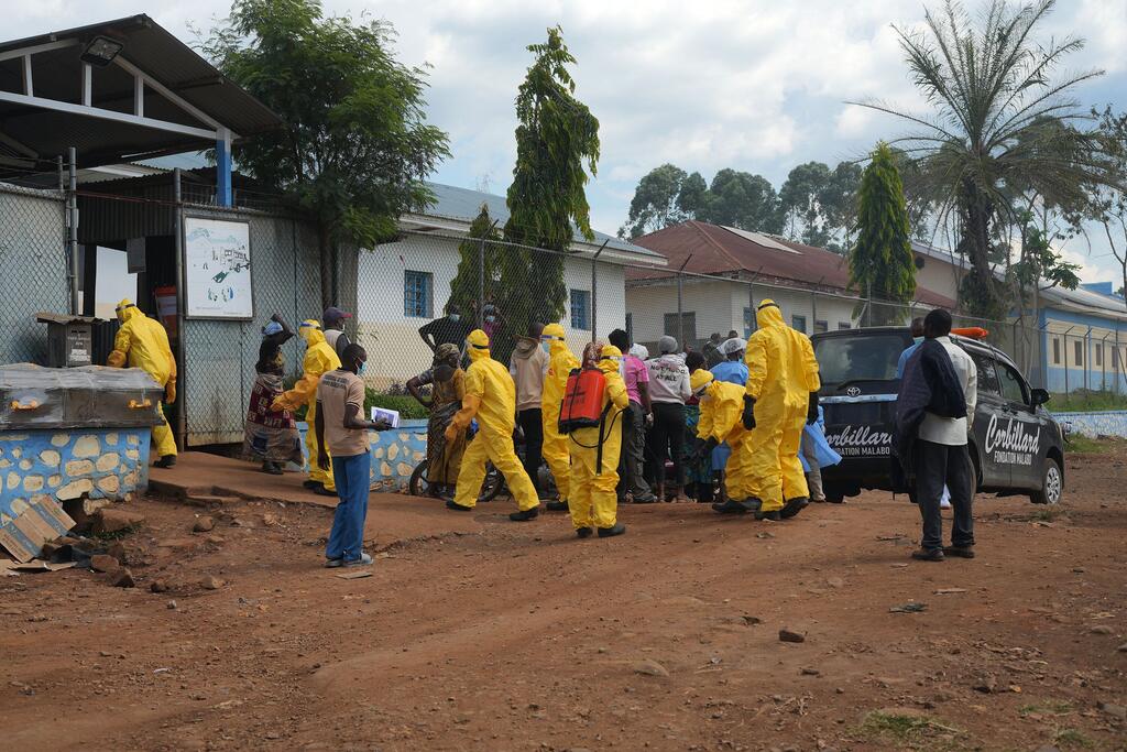 Des agents de santé de l'OMS, vêtus de combinaisons de protection jaunes, distribuent des fournitures dans un établissement de santé à Nyankunde, dans l'Ituri, lors d'une intervention contre une épidémie d'Ebola.