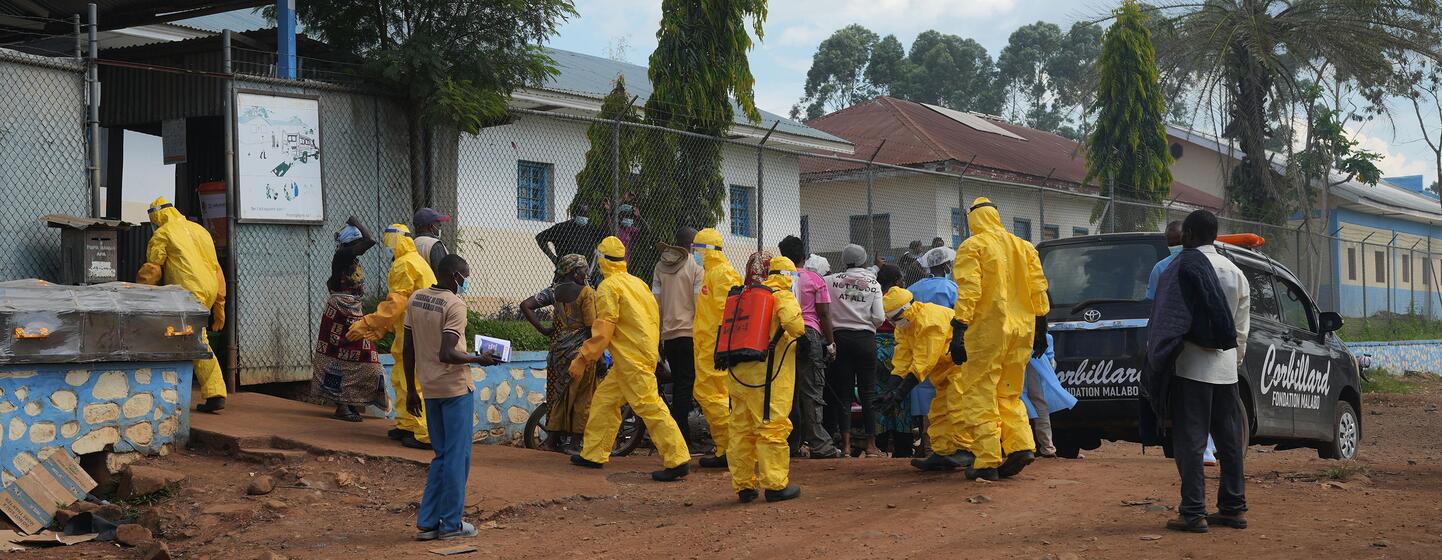 Des agents de santé de l'OMS, vêtus de combinaisons de protection jaunes, distribuent des fournitures dans un établissement de santé à Nyankunde, dans l'Ituri, lors d'une intervention contre une épidémie d'Ebola.