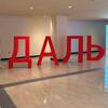 Большое крытое выставочное пространство, где крупными красными объемными буквами написано кириллическое слово «ДАЛЬ» (DAL).