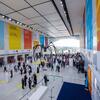 A large spider sculpture stands in a spacious conference hall during the Second World Summit on Sustainable Development in Doha, Qatar, with attendees and UN banners visible.