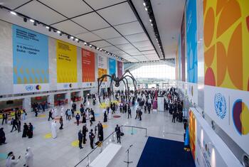 A large spider sculpture stands in a spacious conference hall during the Second World Summit on Sustainable Development in Doha, Qatar, with attendees and UN banners visible.