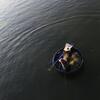 Un pêcheur dans une barque traditionnelle ronde en forme de panier sur une rivière calme au Vietnam.